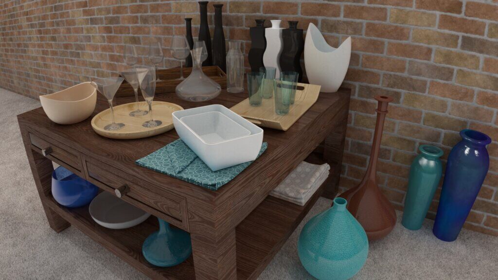 Auf einem Holztisch vor einer Backsteinwand stehen verschiedene Gläser, Schalen, Tabletts und Vasen. Weitere bunte Vasen sind auf dem Boden um den Tisch herum aufgestellt. Auf der Tischplatte und im Regal stehen verschiedene Dekorationsartikel.